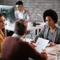 African American financial advisor going through paperwork with her clients while having a meeting in the office.